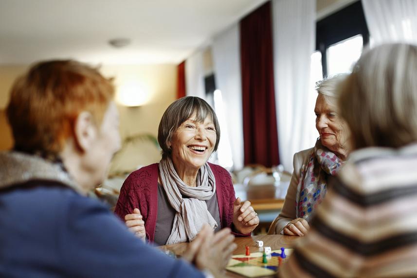 A group of women smiling, playing a board game at a table