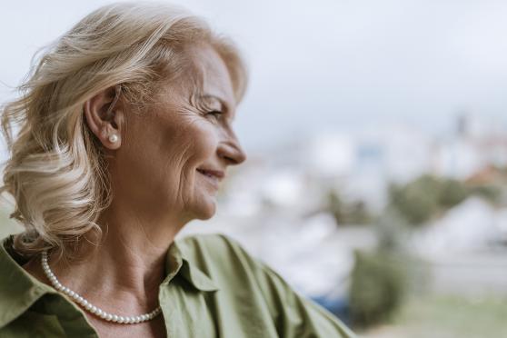 A woman with a hearing aid in her ear, smiling off to the side